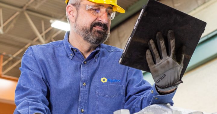 Maintenance technician reviewing equipment performance data on a tablet via a wireless sensor during an industrial inspection