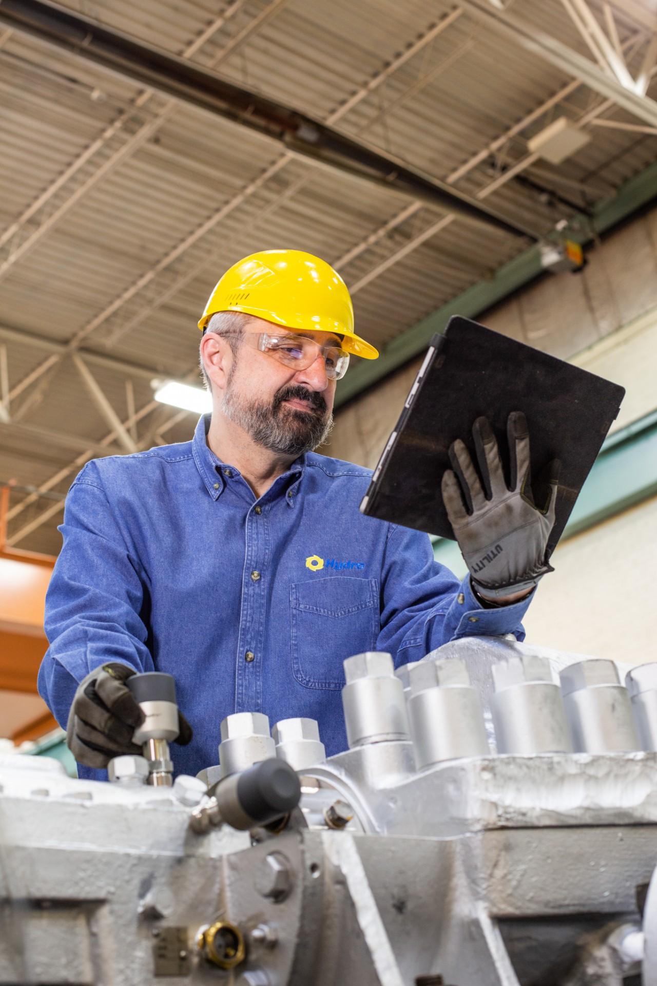 Maintenance technician reviewing equipment performance data on a tablet via a wireless sensor during an industrial inspection
